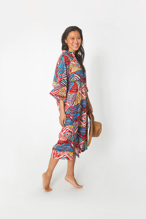 Side view of pretty Asian woman wearing Dessous Loungewear's Bianca caftan in a cotton geometric print.