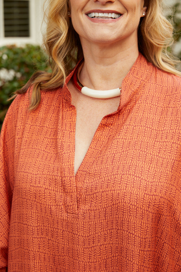 Close up of blond woman wearing Dessous Loungewear Bianca caftan in small orange and red print sustainable Lyocell fabric.