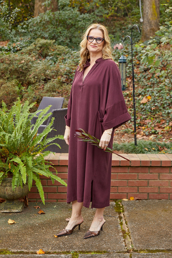 Blonde woman wearing Dessous Loungewear Bianca caftan in plum colored sustainable Lyocell fabric.