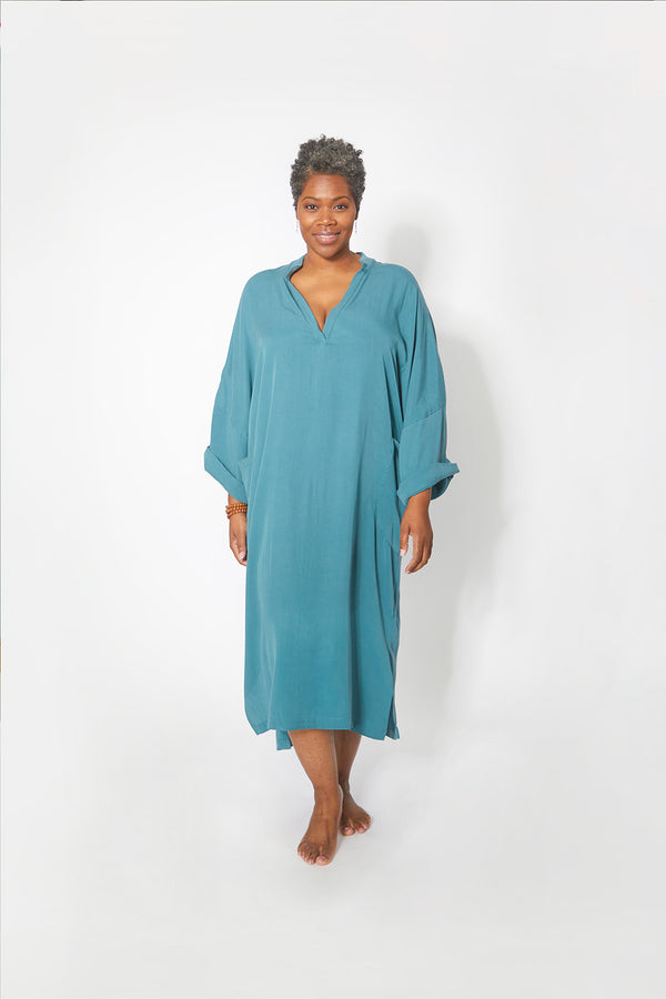 Front view of beautiful black woman wearing Dessous Loungewear's Bianca caftan midi dress in sustainable Lyocell turquoise fabric.
