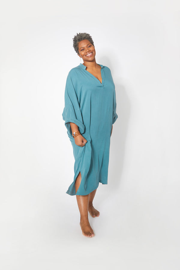 Beautiful black woman wearing Dessous Loungewear Bianca caftan midi dress in sustainable turquoise Lyocell fabric.
