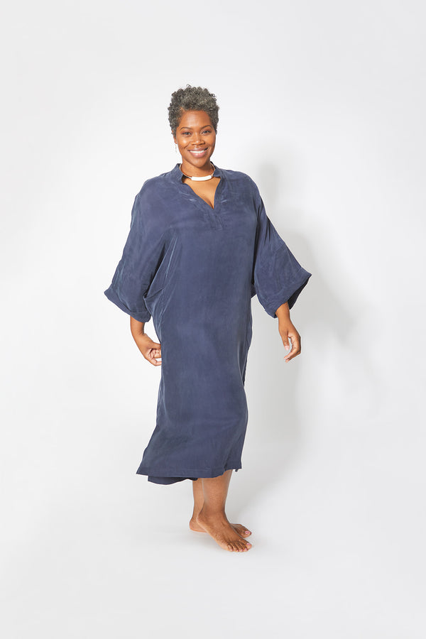 Front view of beautiful black woman wearing Dessous Loungewear Bianca caftan in navy sustainable Cupro fabric.