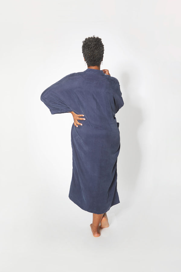 Back view of beautiful black woman wearing Dessous Loungewear Bianca caftan in navy sustainable Cupro fabric.