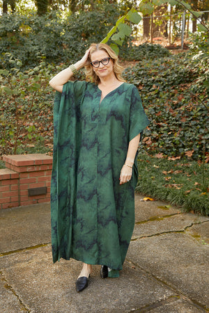 Front view of woman wearing green and navy marble print caftan in eco-friendly Tencel Lyocell fabric. The caftan is maxi-length with a V neckline.